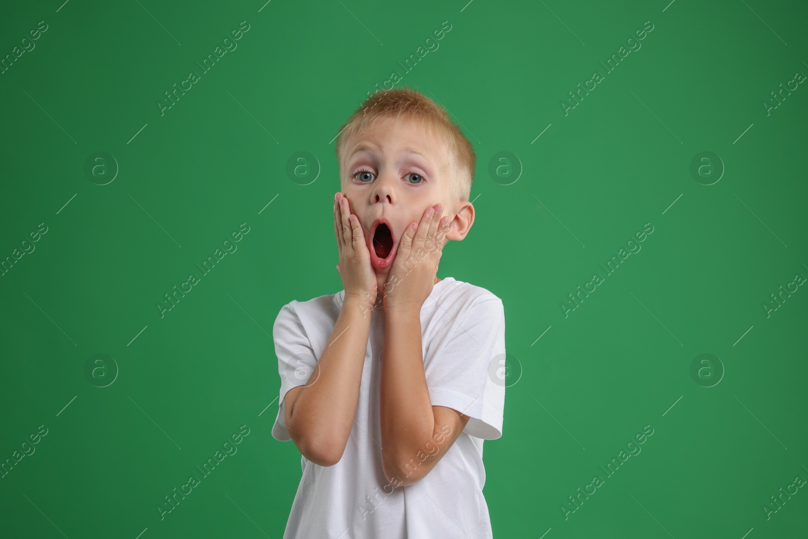 Photo of Portrait of scared little boy on green background