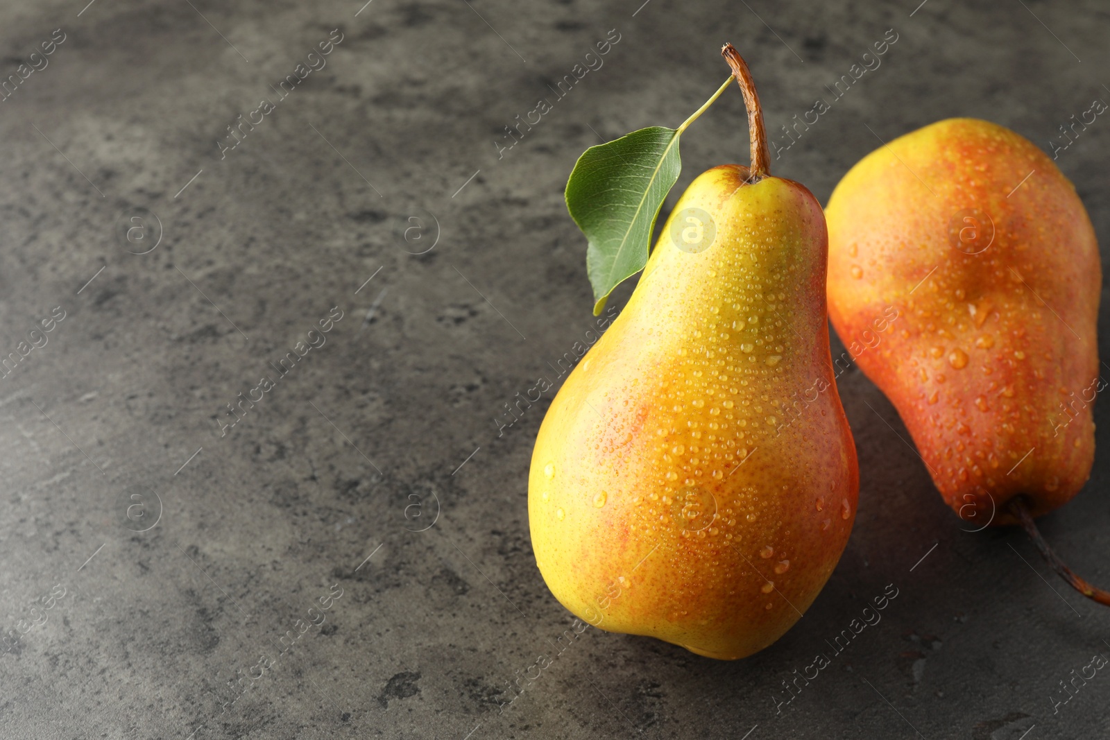 Photo of Two ripe juicy pears on grey table, closeup. Space for text