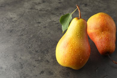 Photo of Two ripe juicy pears on grey table, closeup. Space for text