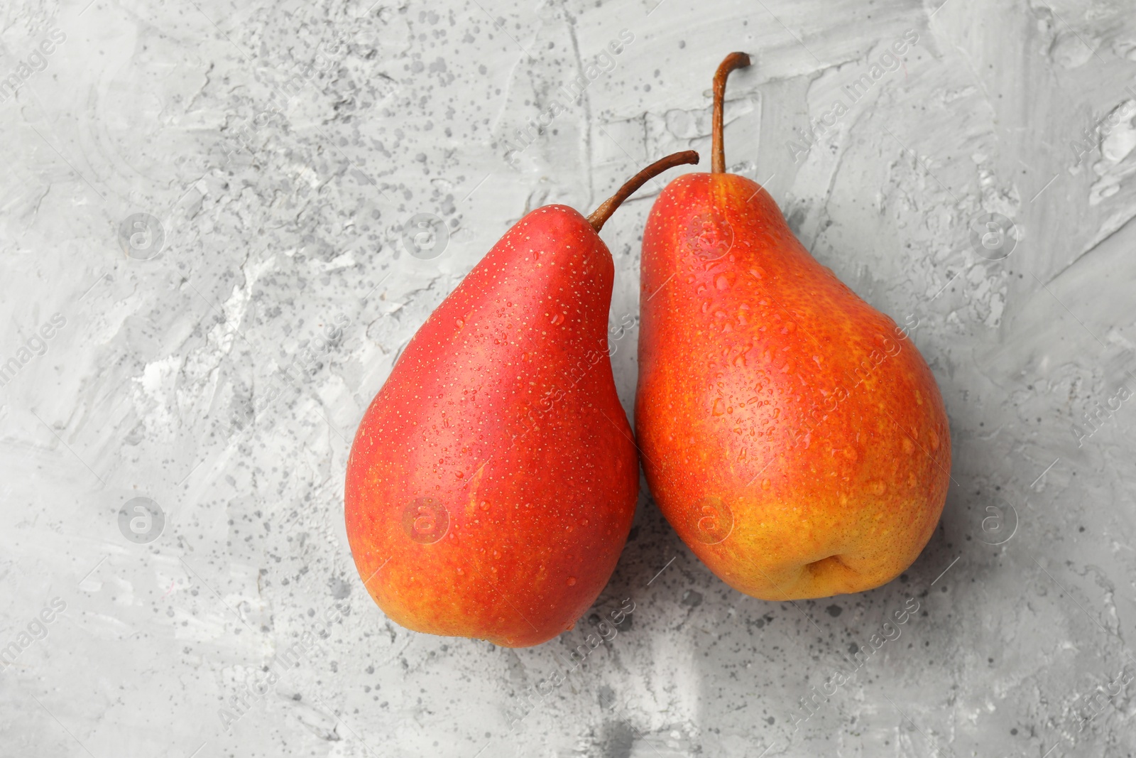 Photo of Two ripe juicy pears on grey table, top view