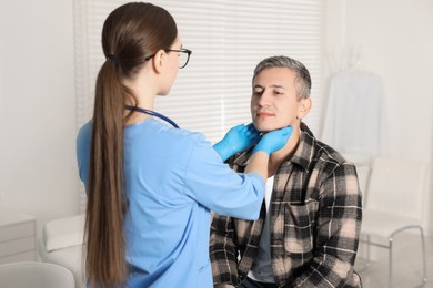 Photo of Doctor examining man's throat in clinic during appointment