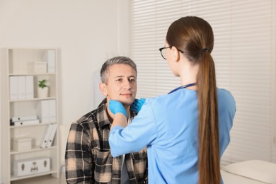 Photo of Doctor examining man's throat in clinic during appointment