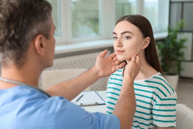 Photo of Doctor examining woman's throat in clinic during appointment