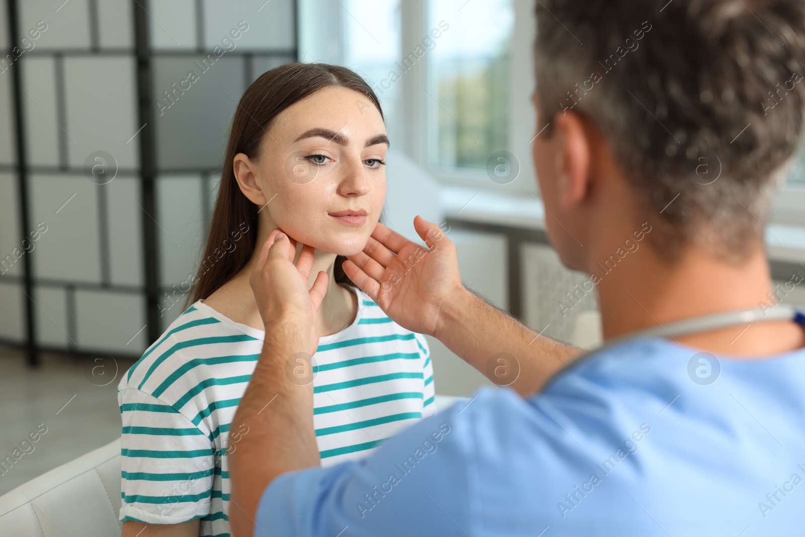 Photo of Doctor examining woman's throat in clinic during appointment