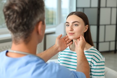 Doctor examining woman's throat in clinic during appointment