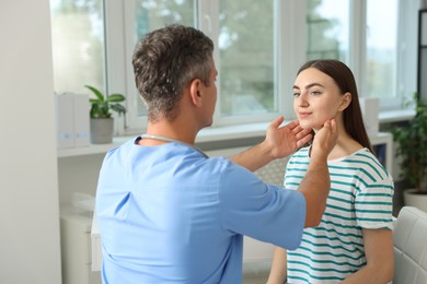 Photo of Doctor examining woman's throat in clinic during appointment