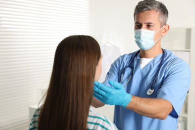 Doctor examining woman's throat in clinic during appointment