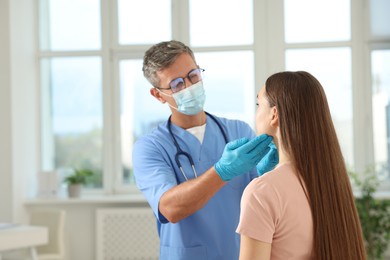 Photo of Doctor examining woman's throat in clinic during appointment