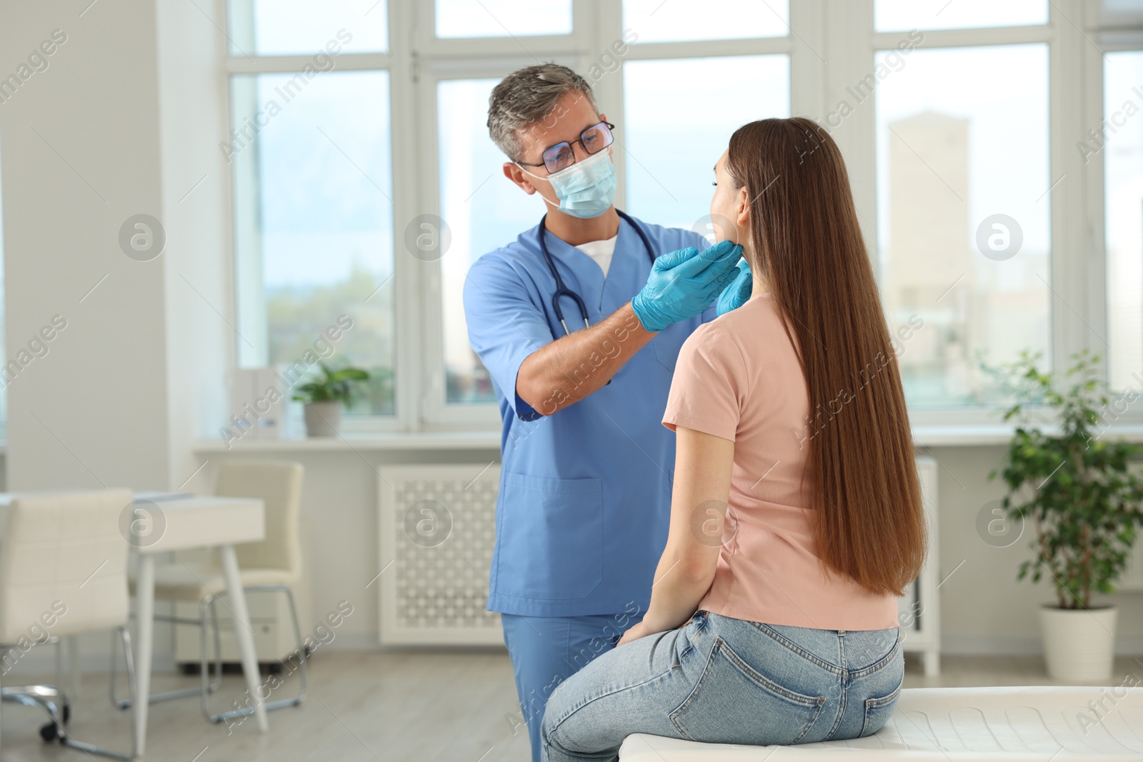 Photo of Doctor examining woman's throat in clinic during appointment