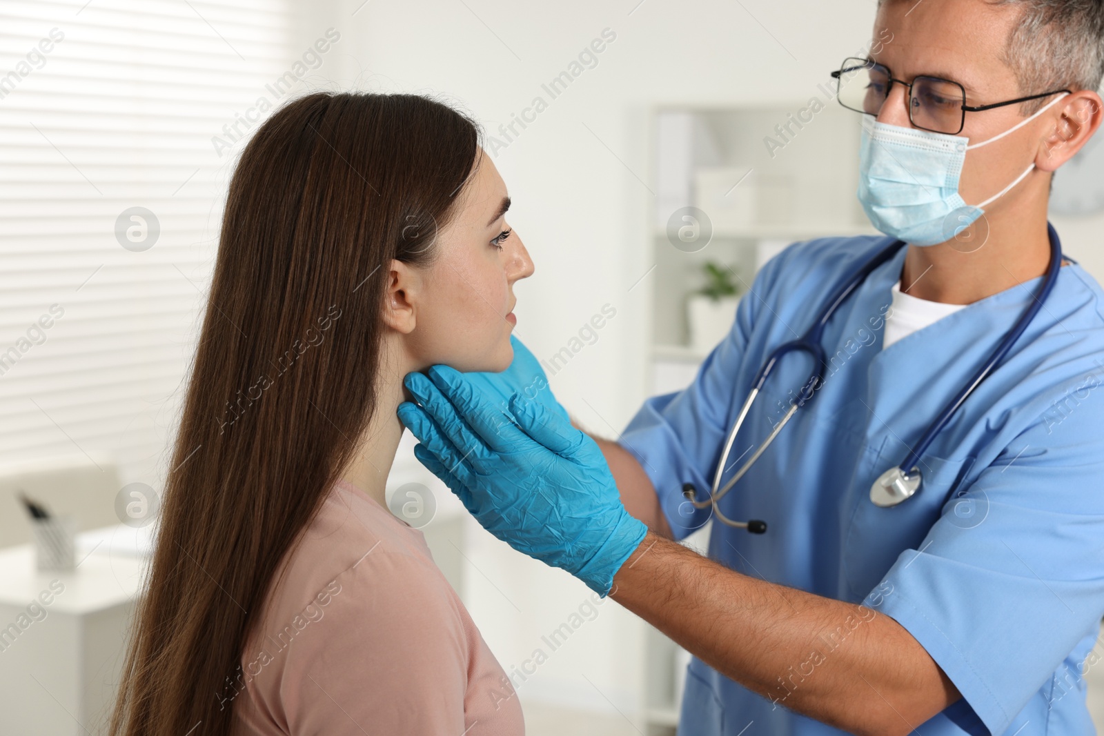 Photo of Doctor examining woman's throat in clinic during appointment