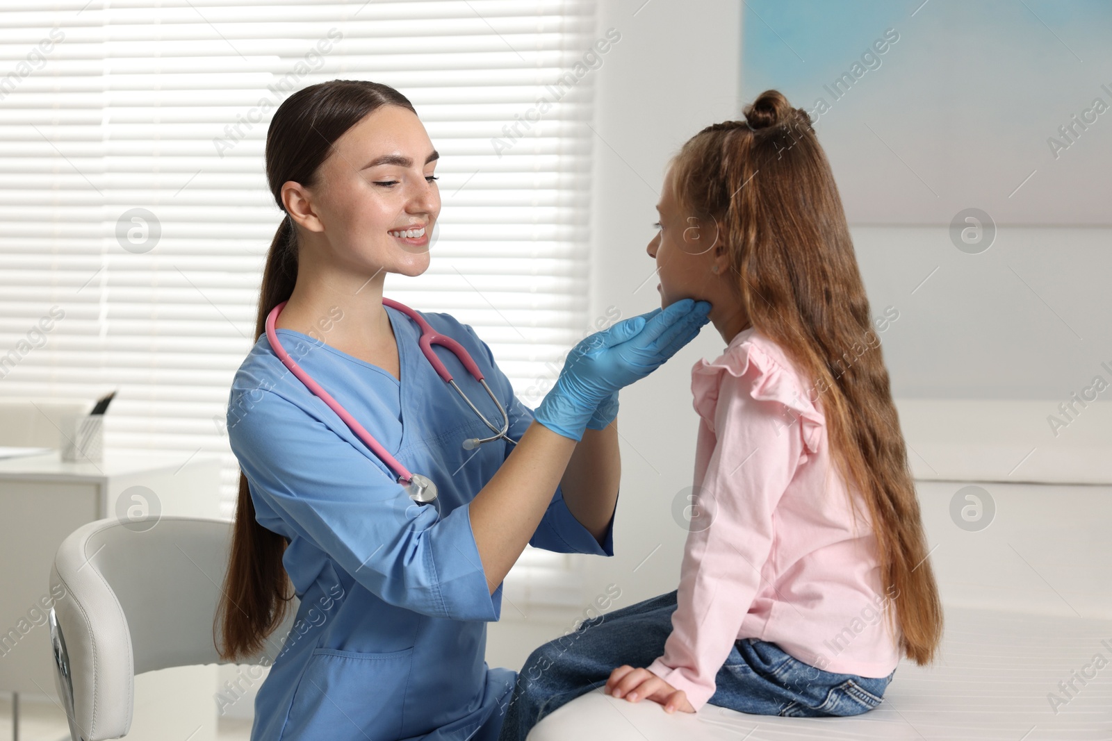 Photo of Doctor examining girl's throat in clinic during appointment