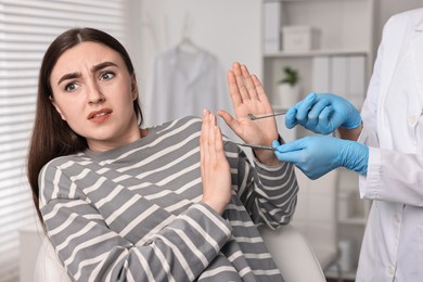 Photo of Dental phobia. Dentist working with scared woman in clinic, closeup