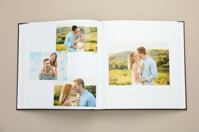 Photo of Open photo album with different photos on beige background, top view