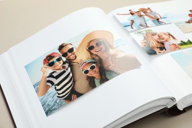 Photo of Open photo album with different photos on beige background, closeup