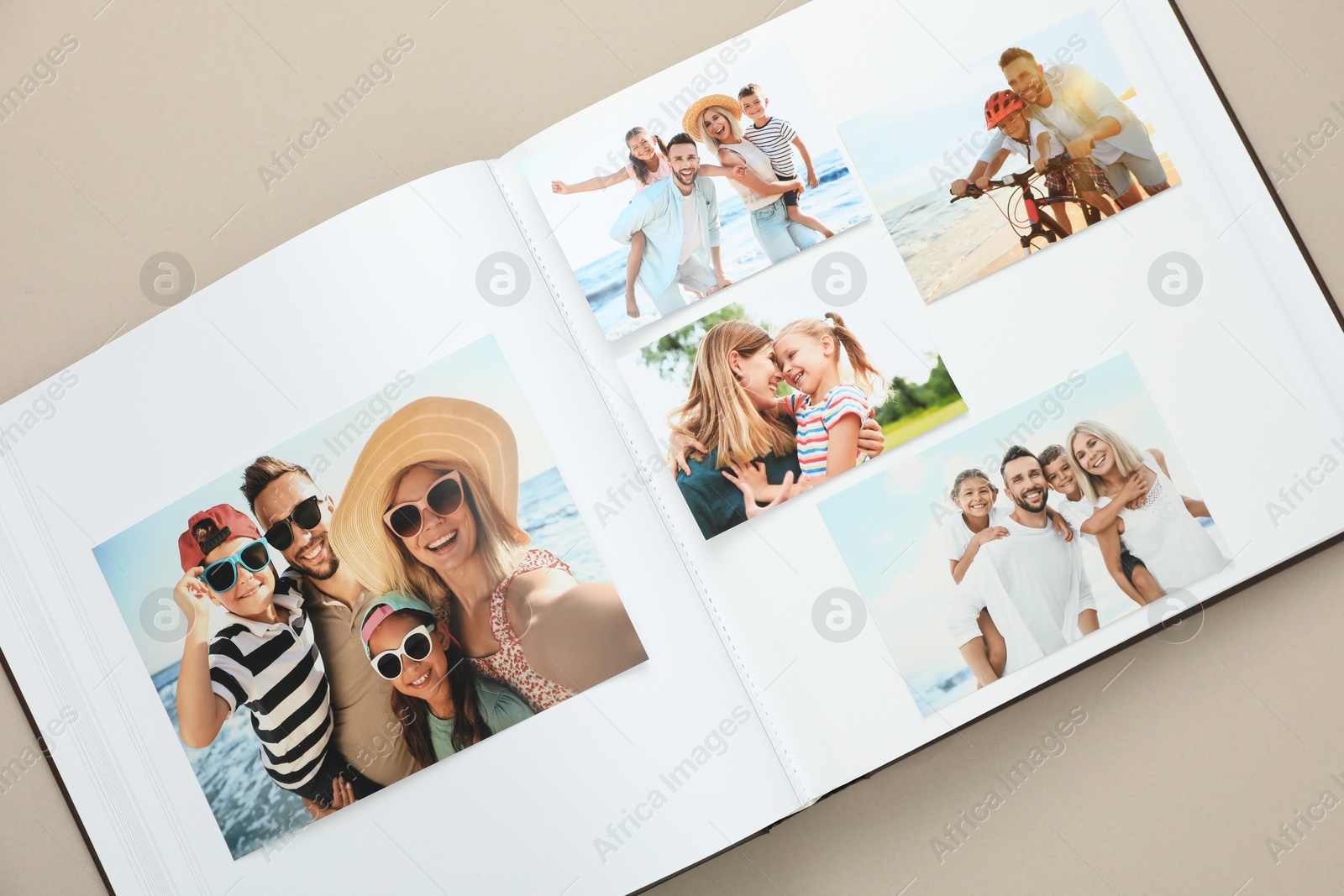 Photo of Open photo album with different photos on beige background, top view