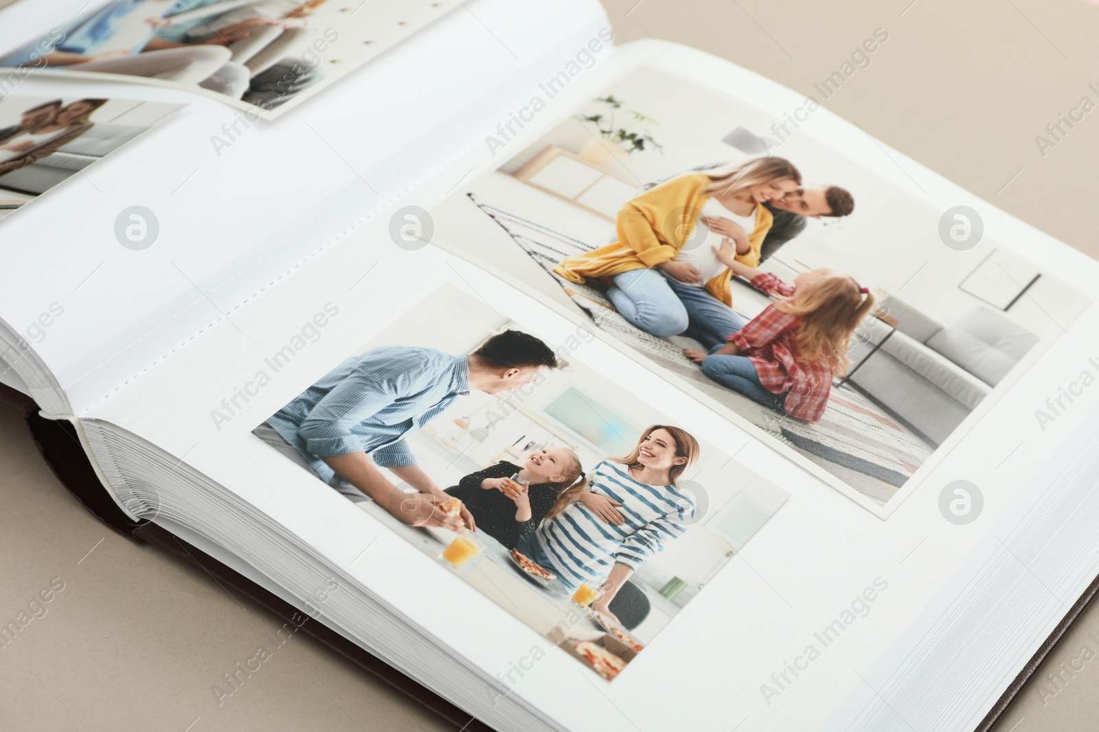 Photo of Open photo album with different photos on beige background, closeup