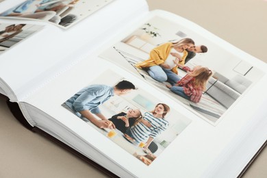 Photo of Open photo album with different photos on beige background, closeup