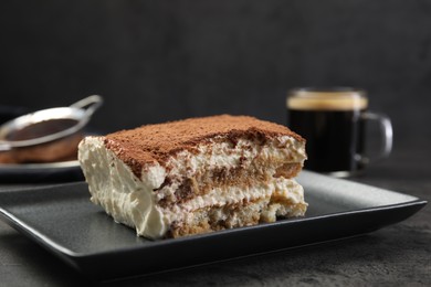 Photo of Piece of tasty tiramisu on black table, closeup