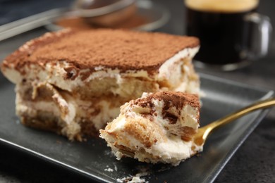 Photo of Eating tasty tiramisu at black table, closeup