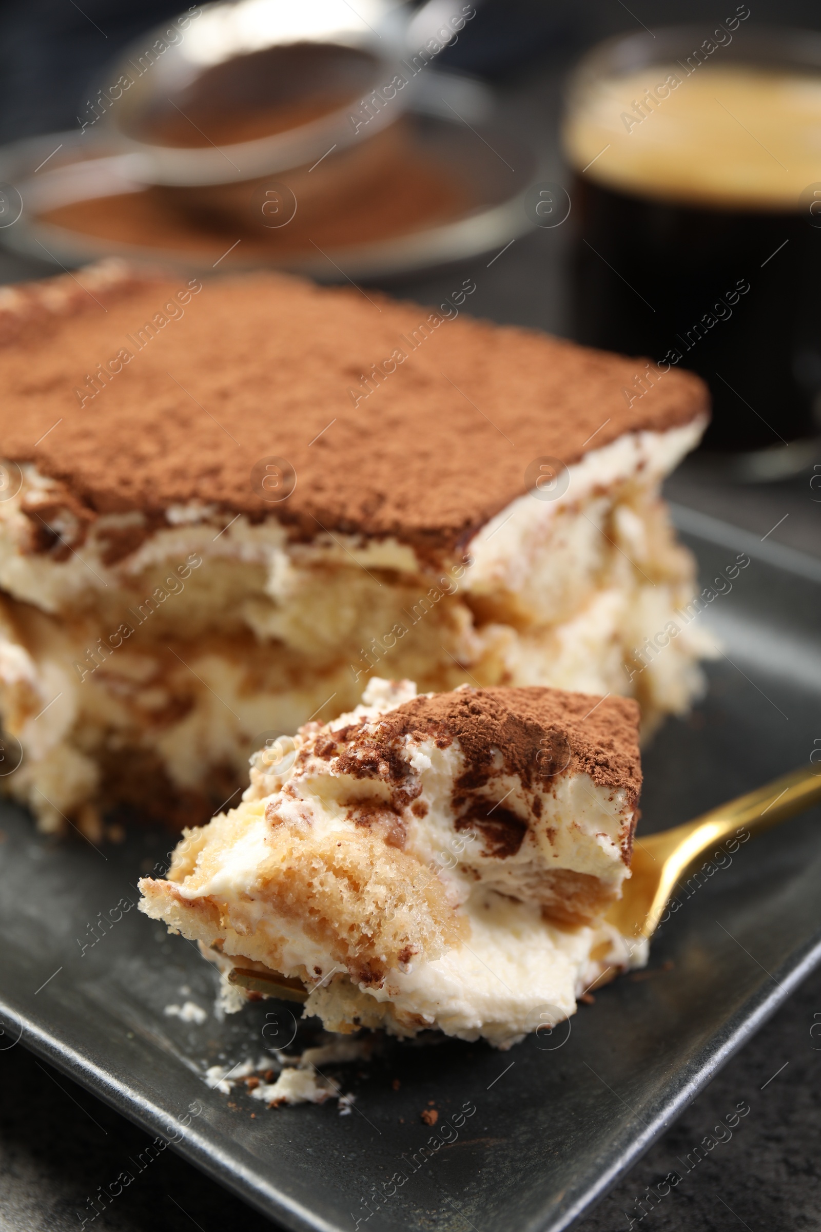 Photo of Eating tasty tiramisu at black table, closeup