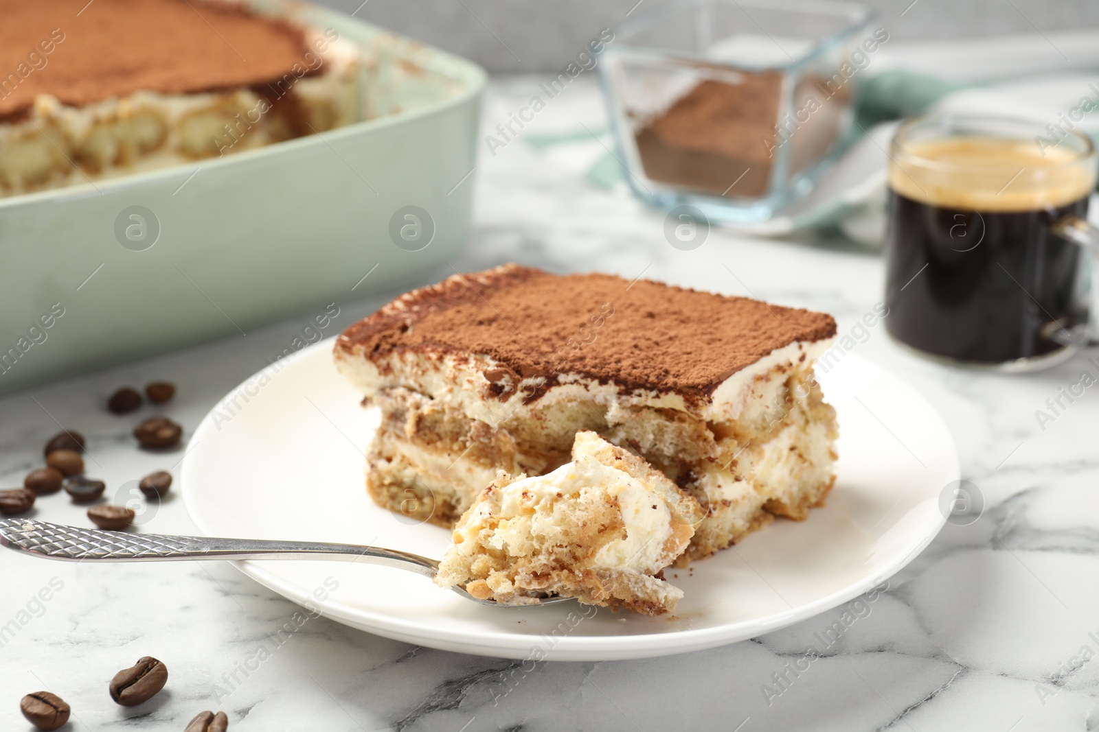 Photo of Piece of tasty tiramisu on white marble table, closeup