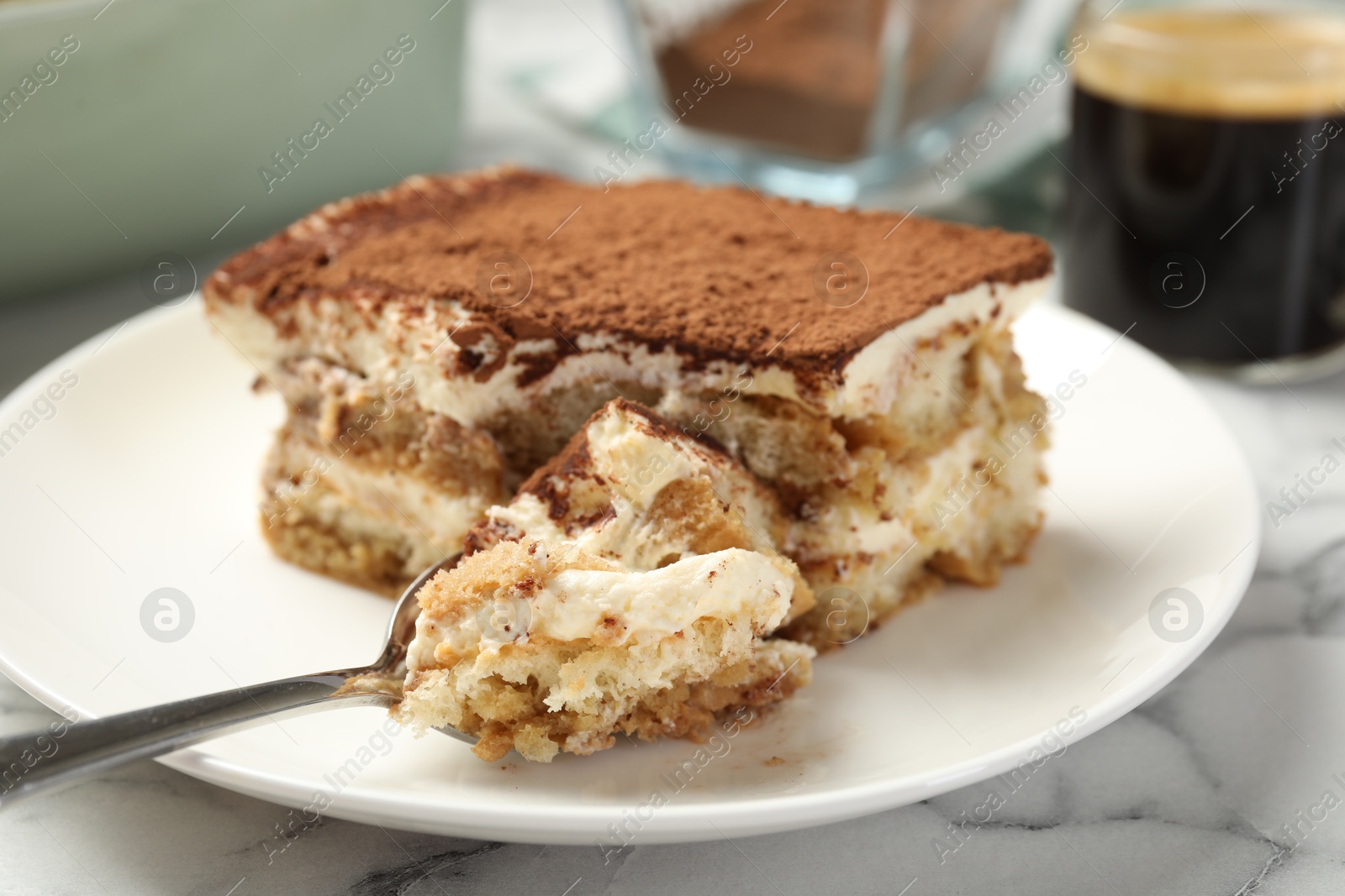 Photo of Piece of tasty tiramisu on white marble table, closeup