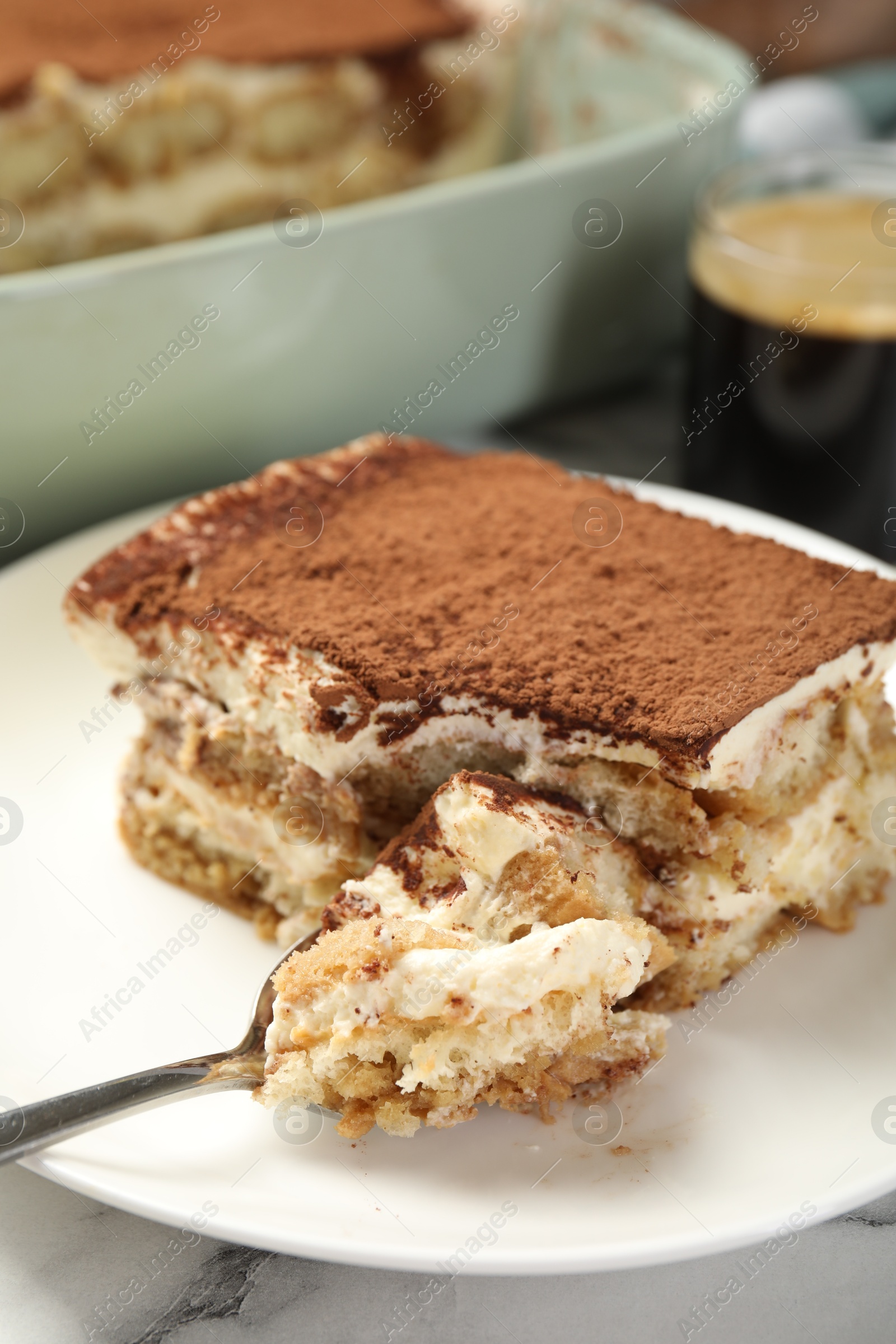 Photo of Piece of tasty tiramisu on white marble table, closeup