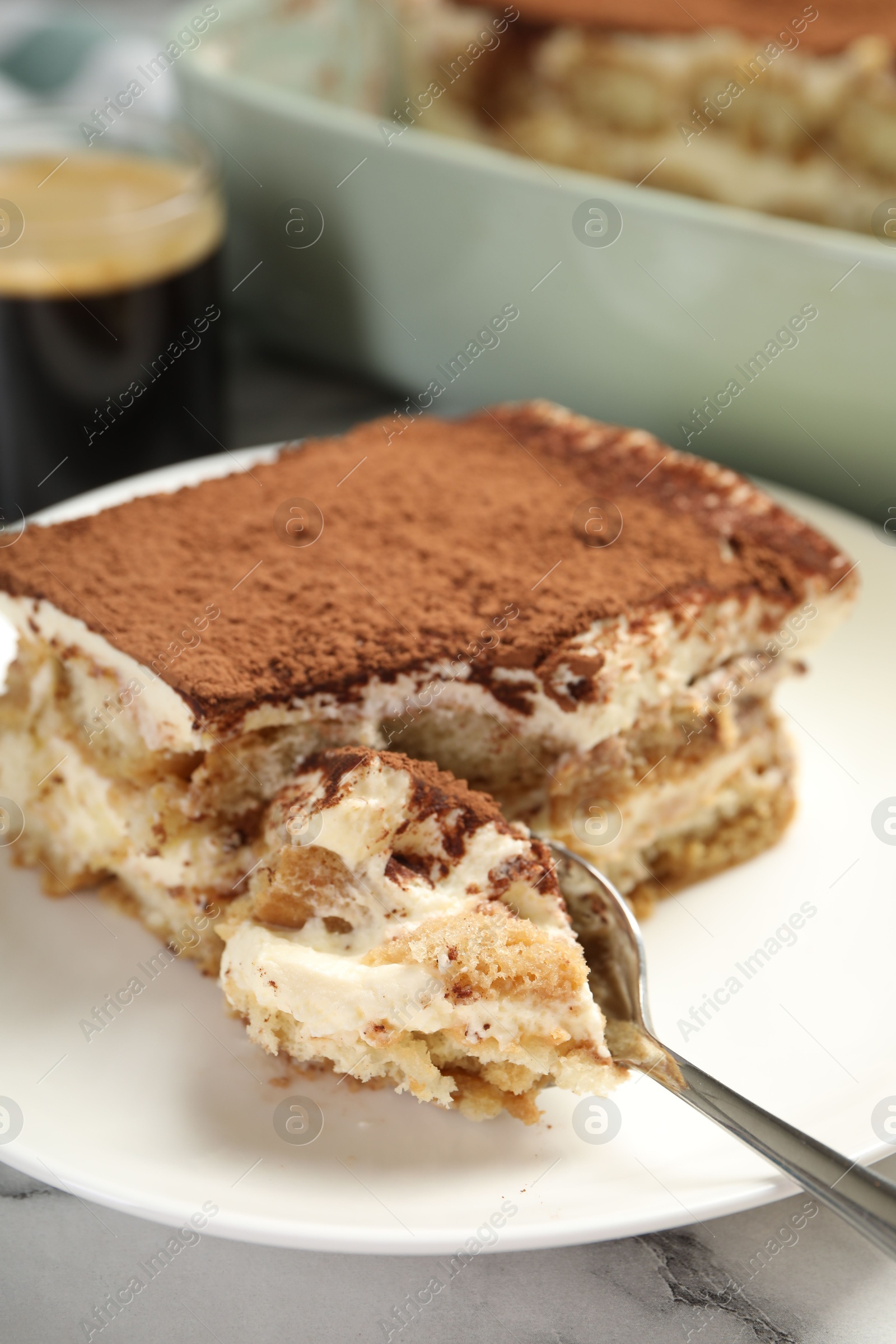 Photo of Piece of tasty tiramisu on white marble table, closeup