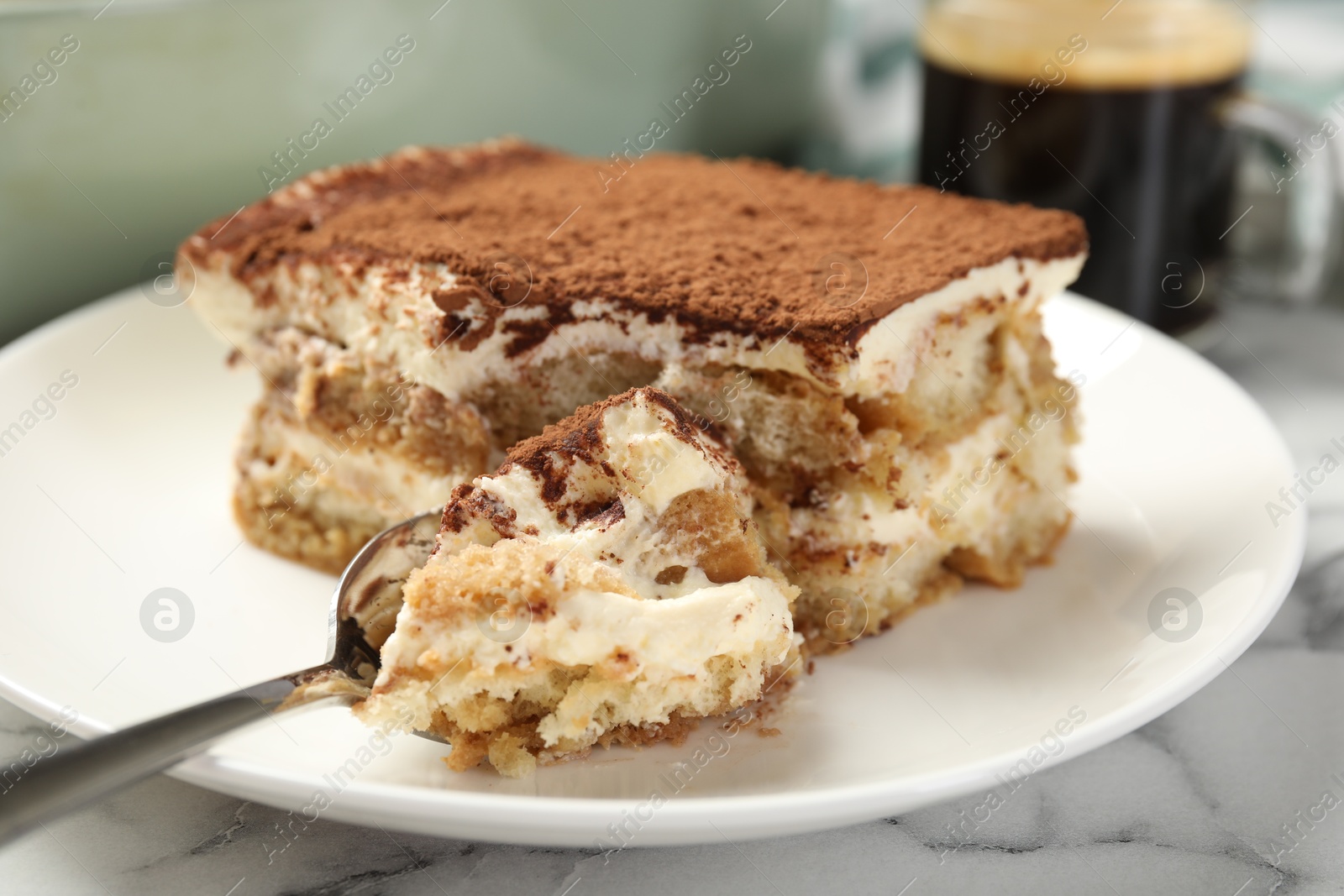 Photo of Piece of tasty tiramisu on white marble table, closeup