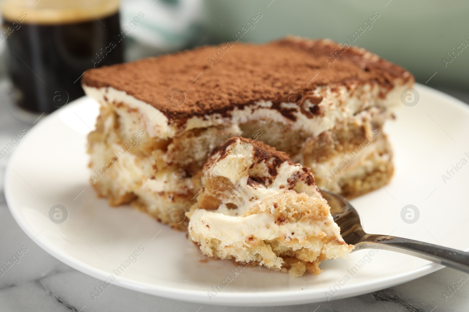 Photo of Piece of tasty tiramisu on white marble table, closeup