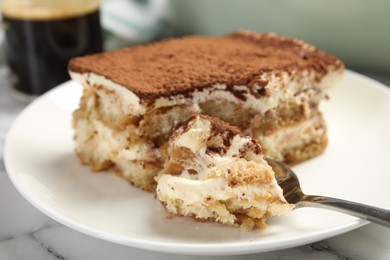 Photo of Piece of tasty tiramisu on white marble table, closeup