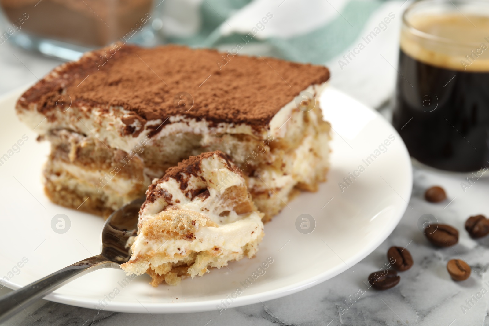 Photo of Piece of tasty tiramisu on white marble table, closeup