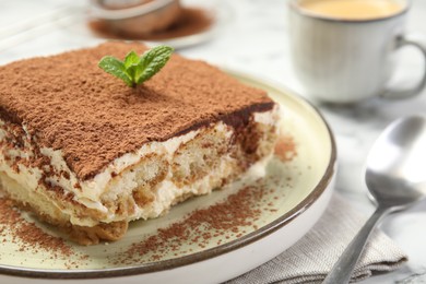 Photo of Piece of tasty tiramisu on white table, closeup