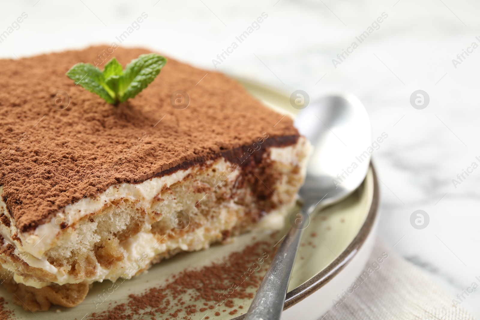 Photo of Piece of tasty tiramisu on white marble table, closeup