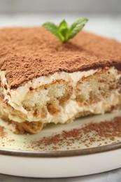 Photo of Piece of tasty tiramisu on white marble table, closeup