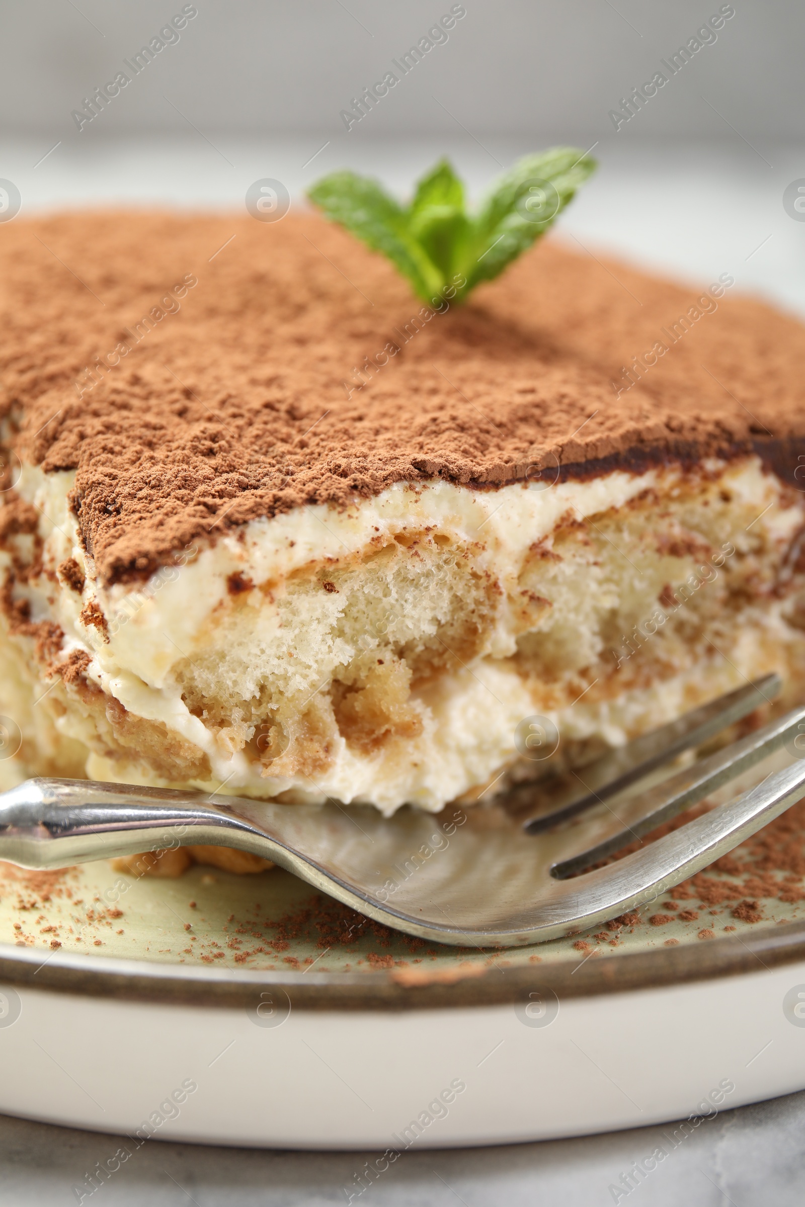 Photo of Piece of tasty tiramisu on white marble table, closeup