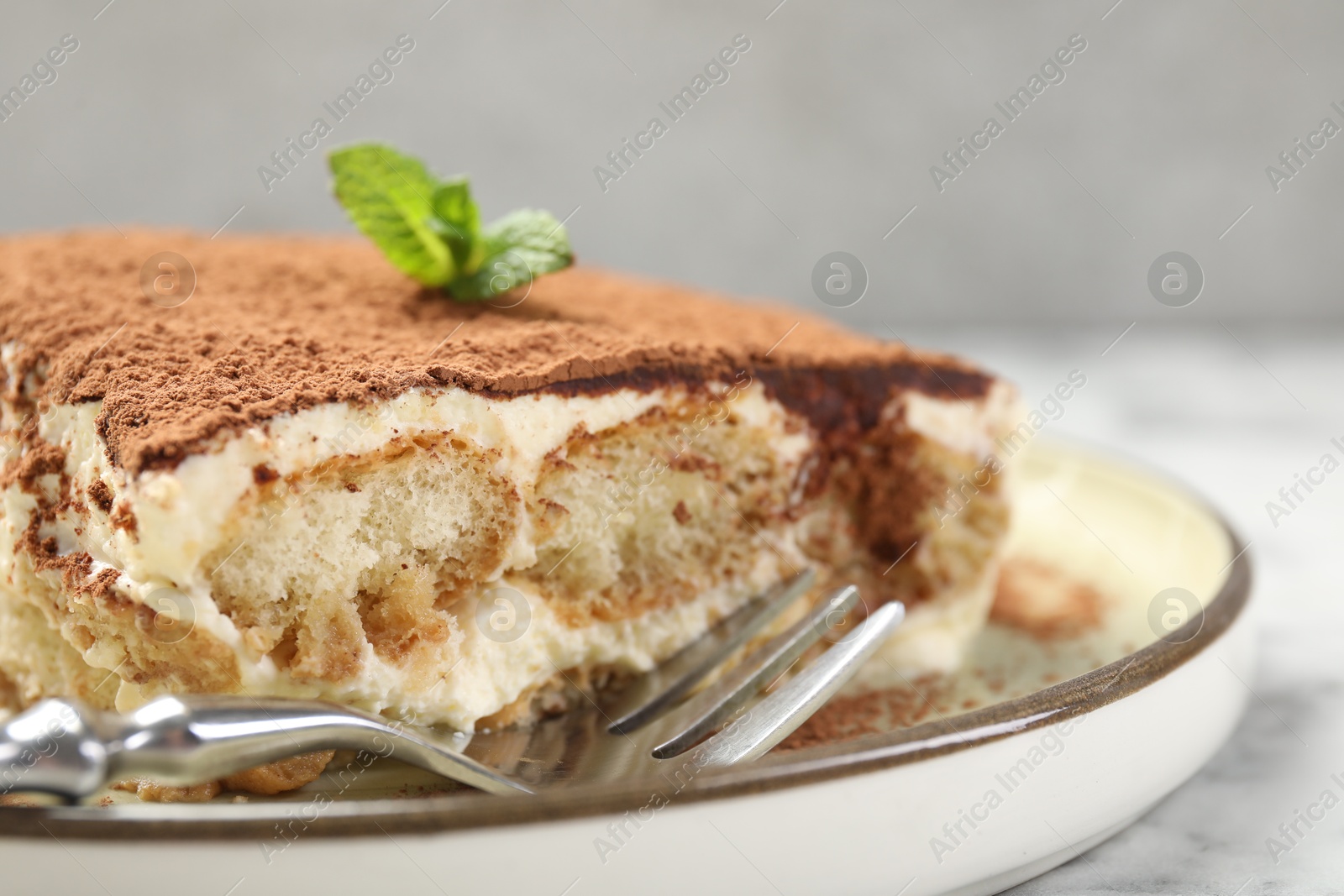 Photo of Piece of tasty tiramisu on white marble table, closeup