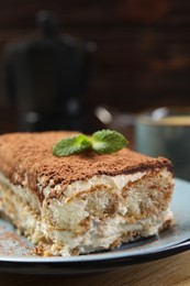 Photo of Piece of tasty tiramisu on wooden table, closeup