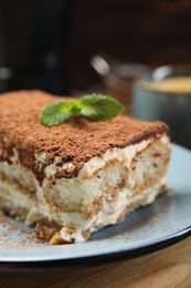 Photo of Piece of tasty tiramisu on wooden table, closeup