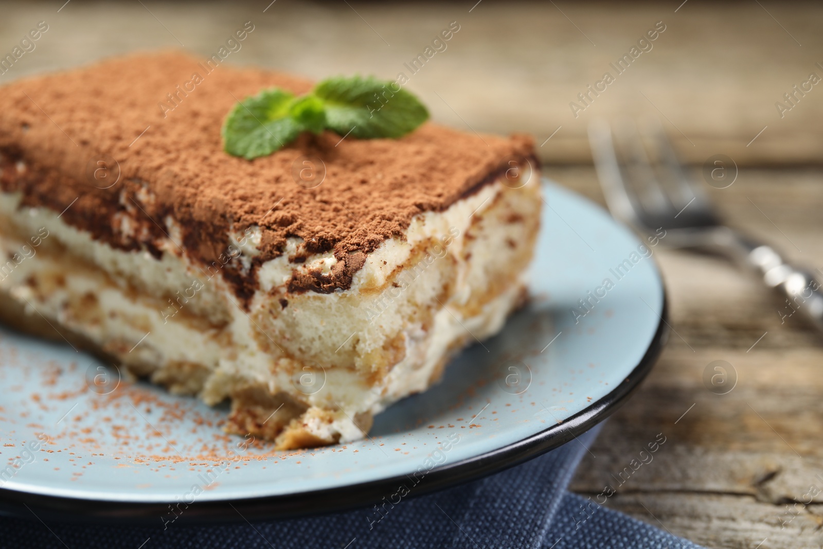 Photo of Piece of tasty tiramisu on wooden table, closeup