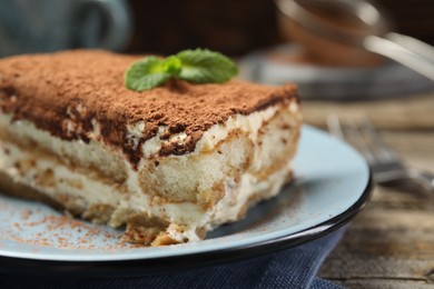 Photo of Piece of tasty tiramisu on wooden table, closeup