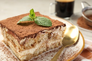 Photo of Piece of tasty tiramisu with fresh mint on table, closeup