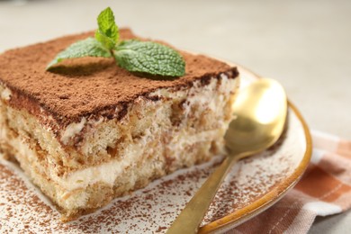 Photo of Piece of tasty tiramisu with fresh mint on table, closeup