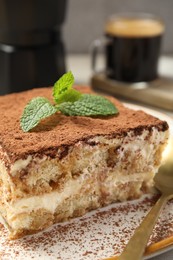 Photo of Piece of tasty tiramisu with fresh mint on table, closeup