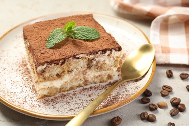 Photo of Piece of tasty tiramisu on beige table, closeup