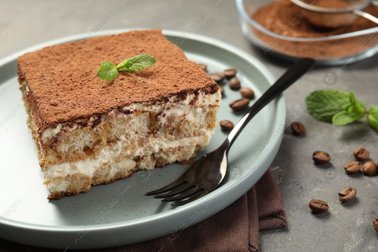 Photo of Piece of tasty tiramisu on grey table, closeup