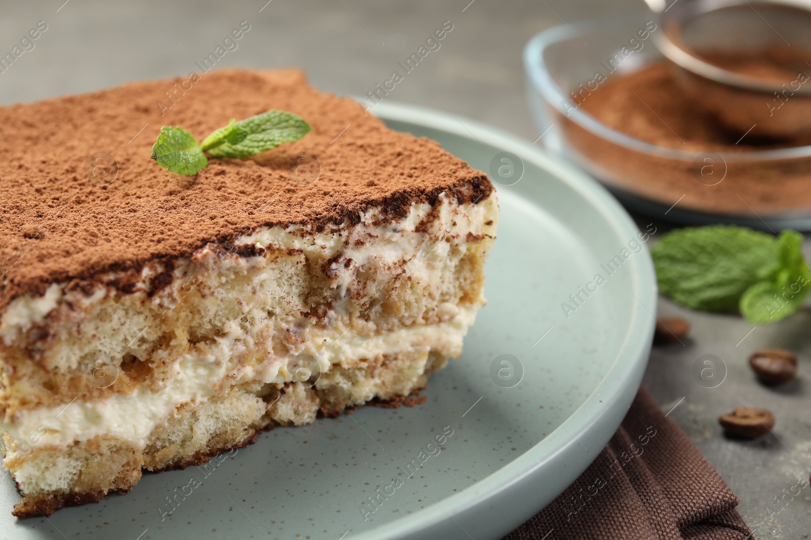 Photo of Piece of tasty tiramisu on grey table, closeup