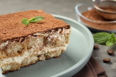 Photo of Piece of tasty tiramisu on grey table, closeup