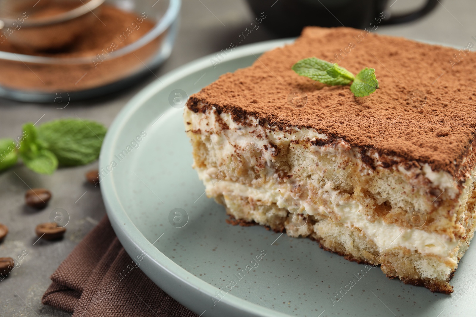 Photo of Piece of tasty tiramisu on grey table, closeup