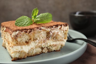 Photo of Piece of tasty tiramisu with fresh mint on table, closeup